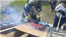 Firefighter Sawing Through a Plank While on a Ladder