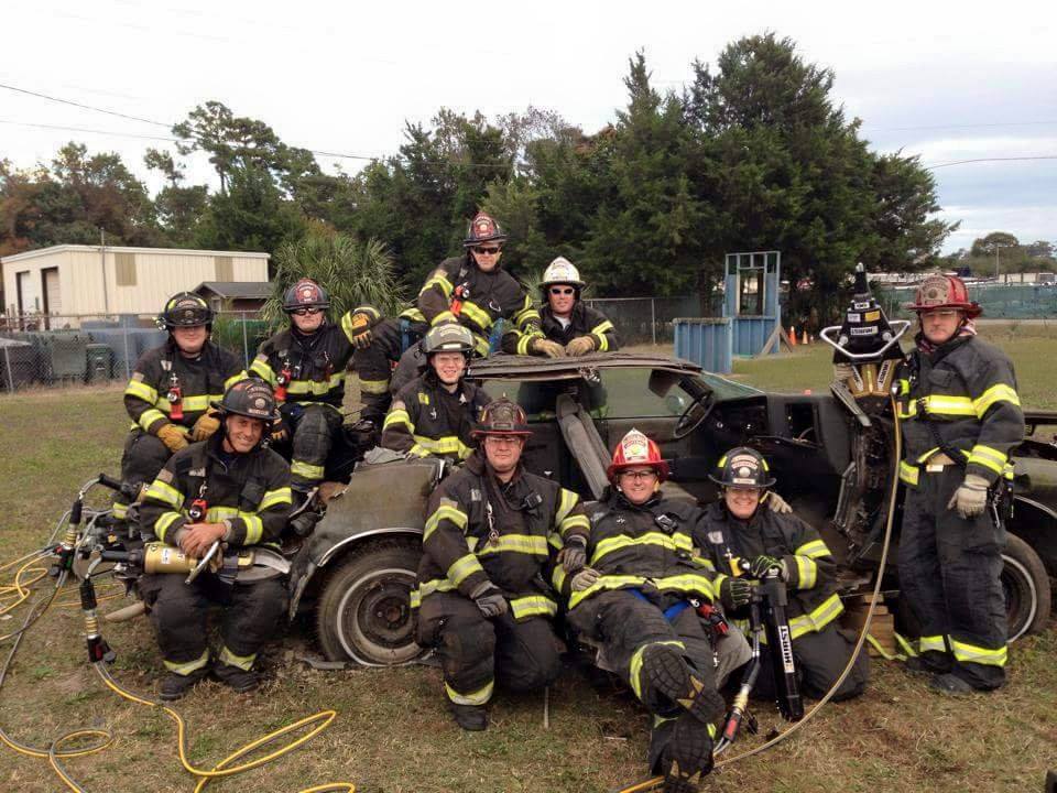 Group of Firefighters Around a Burned Car